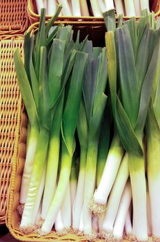 Group of whole leek onions in a basket at marketplace
