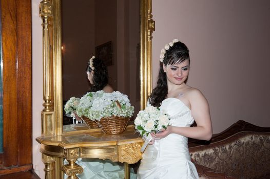 Beautiful bride near mirror in wedding palace