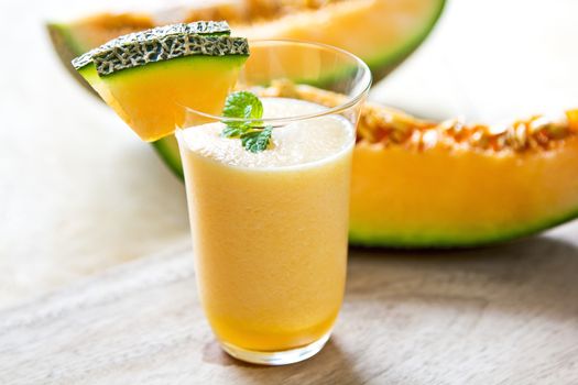 Cantaloupe smoothie in a glass by fresh cantaloupe