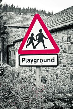 A playground warning sign with selective color desaturation