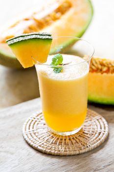 Cantaloupe smoothie in a glass by fresh cantaloupe