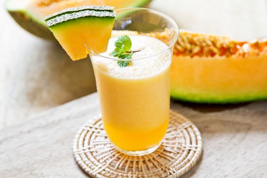 Cantaloupe smoothie in a glass by fresh cantaloupe