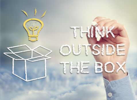 Think outside the box concept with idea lightbulb and open box drawing in chalk