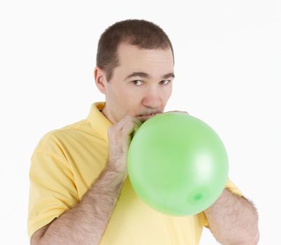 man inflates a green ball on a light background