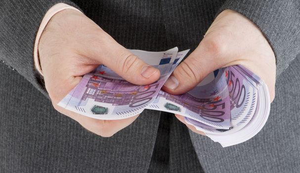 stack banknotes of 500 euro in male hands on a gray background