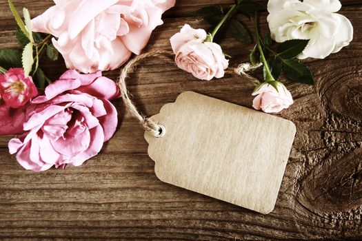 Handmade paper tag with string and roses on a rustic wooden table