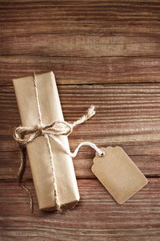 Rectangular present with handmade tag and string ribbon on a rustic wooden table 