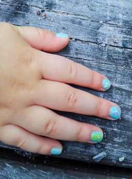 Child with flower paint manicure, towards old wood