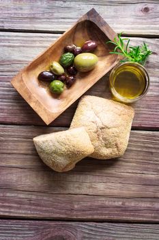 Assorted pickled olives with bread and olive oil on a rustic wooden table