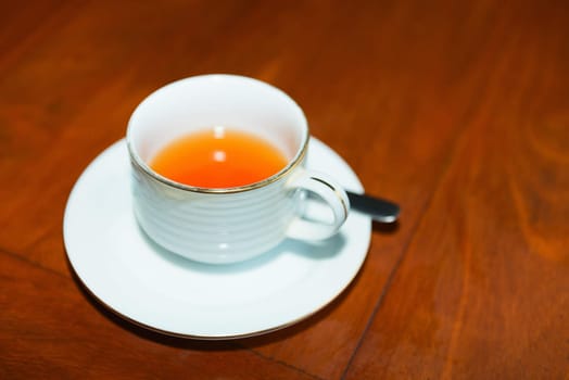 Cup of fresh tea on red brown wooden table in cafe. Selective focus on the cup front edge. 