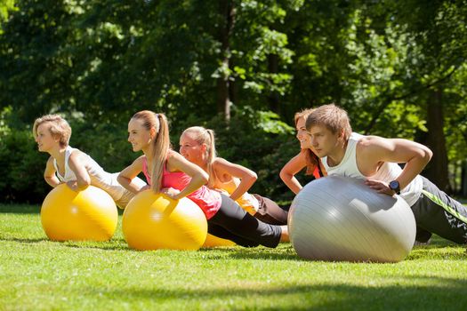 Young caucasians working out in a park with the fitness balls