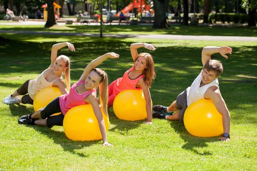 Young caucasians working out in a park with the fitness balls