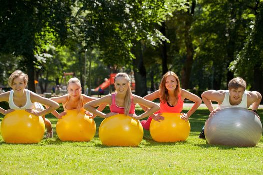 Young caucasians working out in a park with the fitness balls