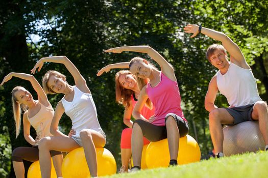 Young caucasians working out in a park with the fitness balls