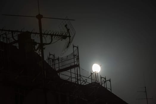 Full moon over the roofs of housed and a scaffolding