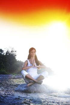 Young woman practicing yoga  near the ocean