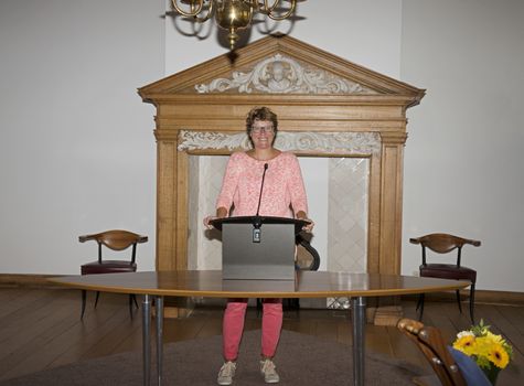 woman standing behind the desk and speaking through microphone