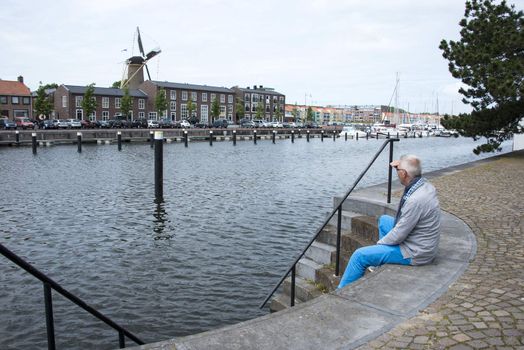 man sitting on the strairs to the water and thinking