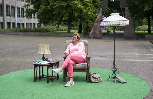 Adult woman thinking and sitting on chair in a park with table and lamp