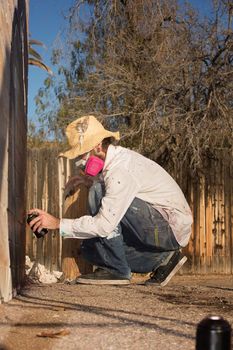 Man crouching on the ground using spray paint on a wall