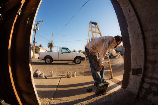 Wide angle view of man with spray paint cans and ladder