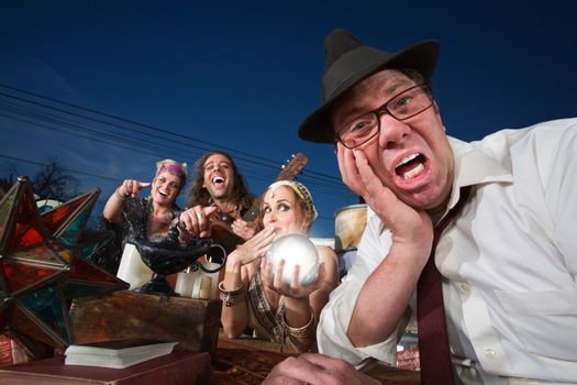Embarrassed white businessman next to giggling fortune teller