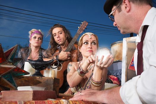 Beautiful fortune teller with glowing crystal ball with customer