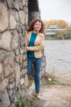 Beautiful sexy brunette girl poses near stone wall