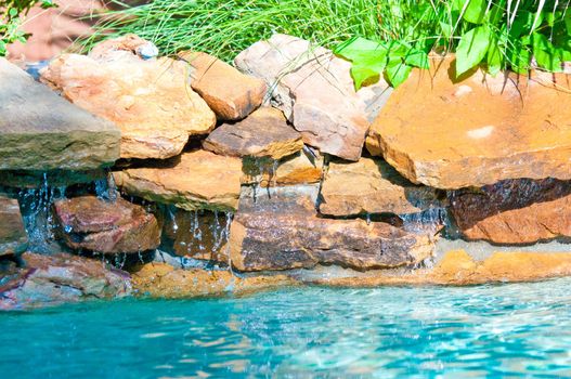 Waterfall falling into a aqua blue lagoon swimming pool