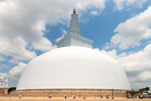 ANURANHAPURA, SRI LANKA - APR 16: Pilgrims go round white sacred stupa Ruwanmalisaya dagoba on Apr 16, 2013 in Anuradhapura, Sri Lanka