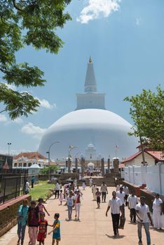 ANURANHAPURA, SRI LANKA - APR 16: Pilgrims pass central entrance to white sacred stupa Ruwanmalisaya dagoba on Apr 16, 2013 in Anuradhapura, Sri Lanka