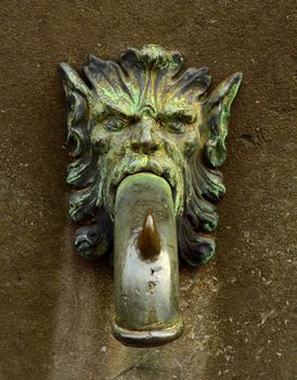 A Grungy Ornamental Street Faucet Shaped Like A Lion's Head