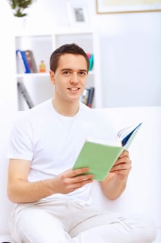 Young handsome man at home with a book
