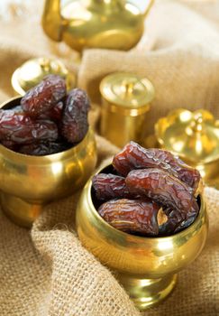 Dates. Dried date palm fruits or kurma, ramadan food which eaten in fasting month. Pile of fresh dried date fruits in golden metal bowl.