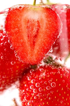 Strawberries with bubbles in water close-up as background