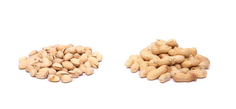 A bunch of pistachios and a bunch of  peanuts on the white background.