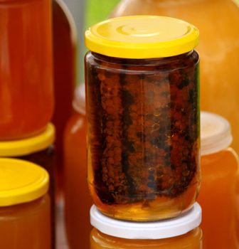 A honeycomb and a honey in a glass jar