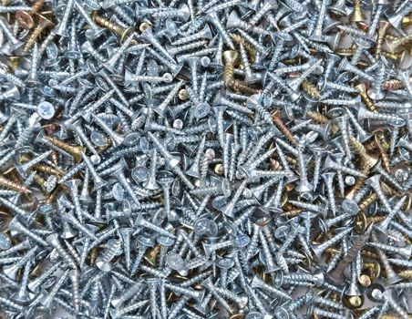 Zinked and anodized screws on a whole background. Texture.