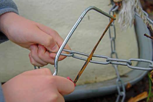 A pair of hands holding a saw and chain