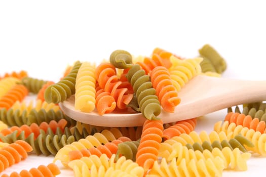 Colorful pasta with wooden spoon on white background.