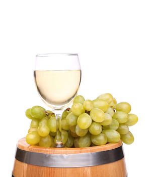 Ripe grapes and wine glass on a wooden vintage barrel isolated on a white background