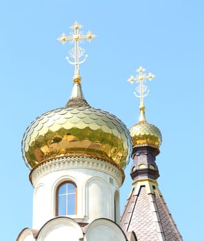 Golden dome of the Orthodox church on the blue sky background partially covered with snow.