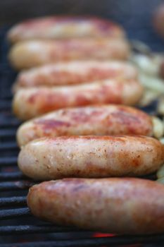Sausages on grill with onions. Row. Close-up. Whole background.