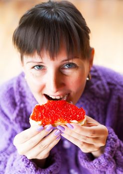  Woman eating the sandwich with red caviar 