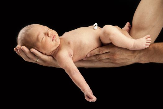 Newborn boy lying on his dad's arms over black