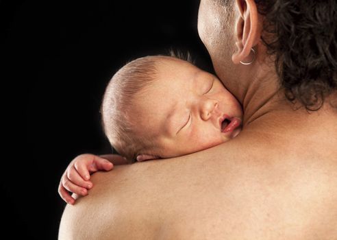 Newborn boy sleeping on his dad's shoulder over black