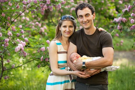 Young caucasian couple with newborn son outdoors in spring