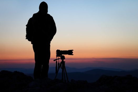 Silhouette of a photographer with his camera on a hilltop