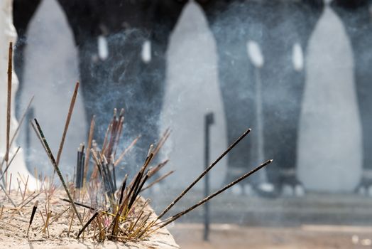 Incense sticks in a Buddhist temple with elephants on background