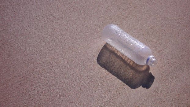 Empty plastic bottle on sandy beach